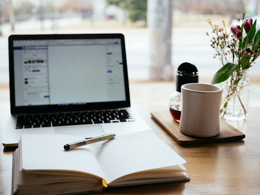 Open notebook on a table in front of a computer