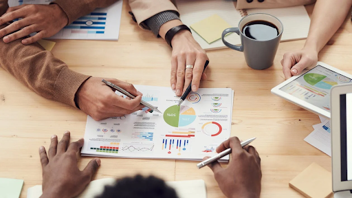 Four people discussing a paper with charts on it